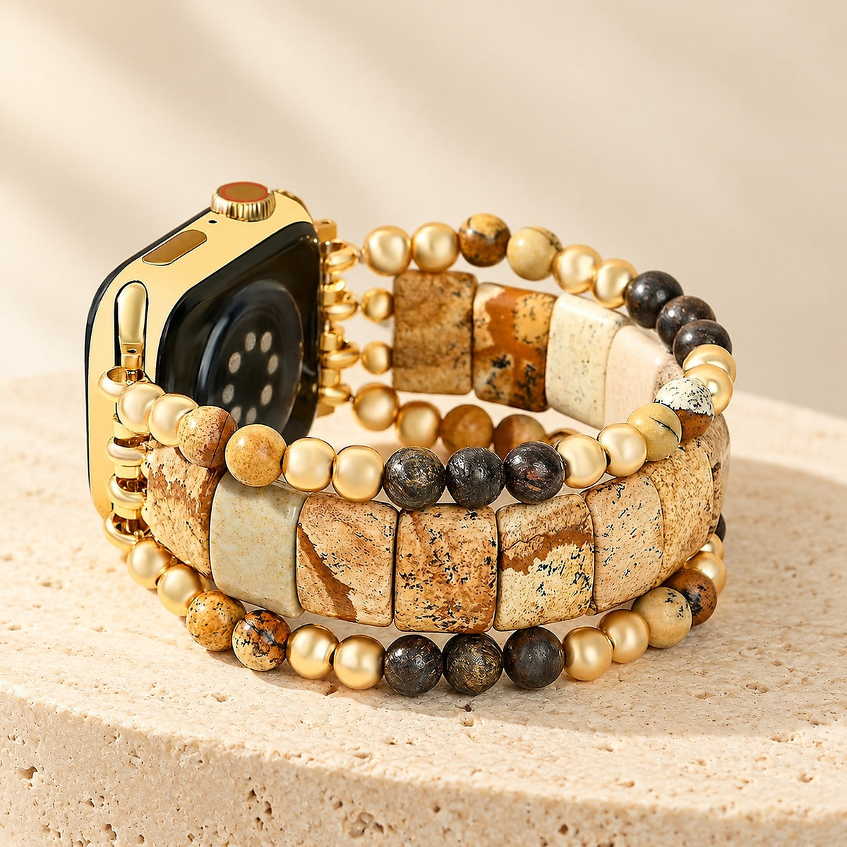 Sacred Ground picture jasper stretch Apple Watch strap on a gold Apple Watch, standing on a travertine pedestal